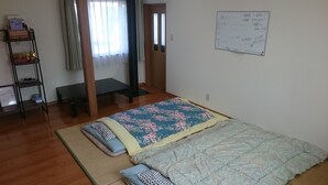 Une chambre à coucher avec un lit, une étagère contenant divers objets, un banc et un tableau blanc avec des inscriptions.