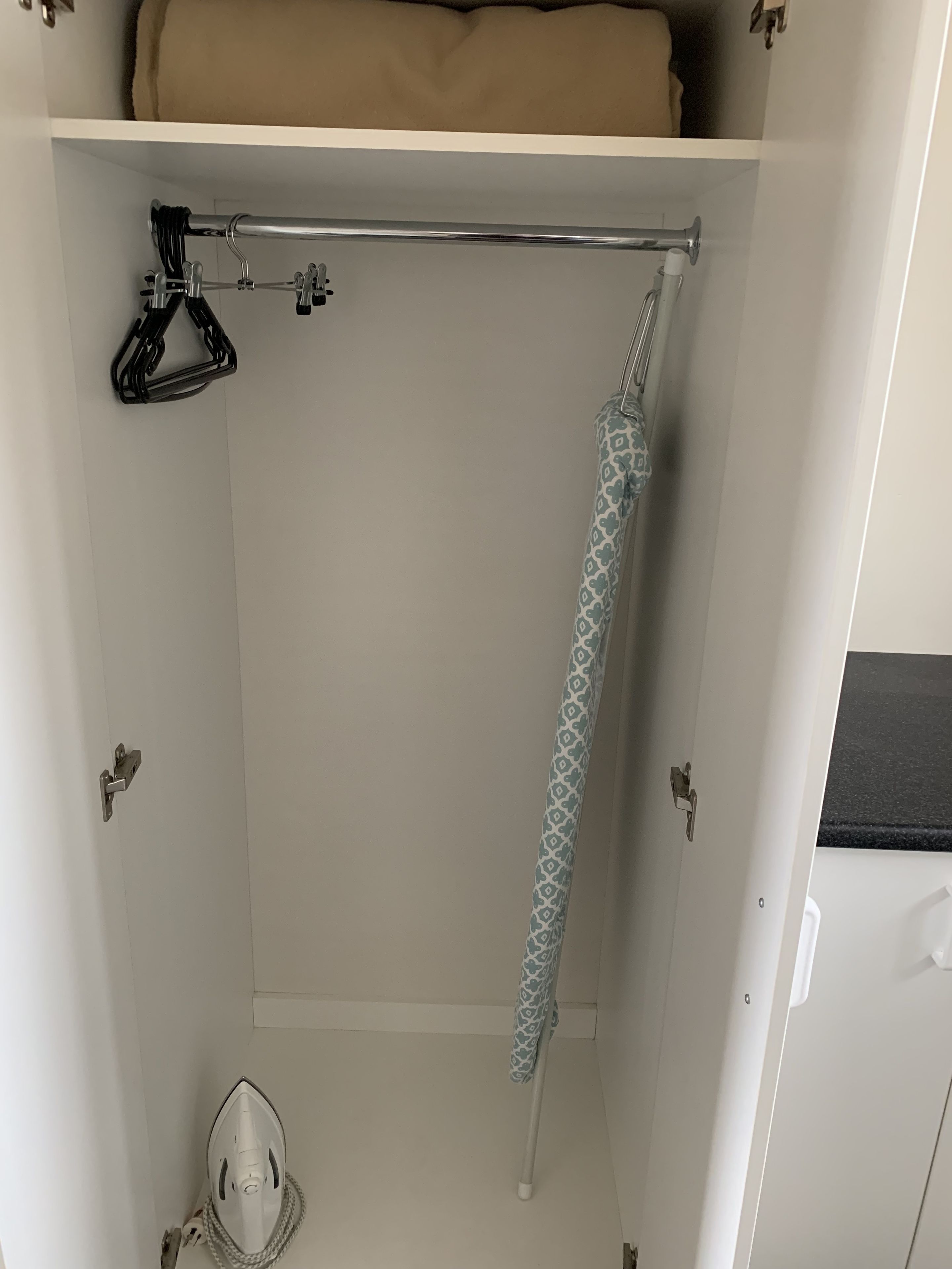 Ein Schrank mit Kleiderhängevorrichtung, Handtuchhalter und einer Tür, an der ein Handtuch hängt.