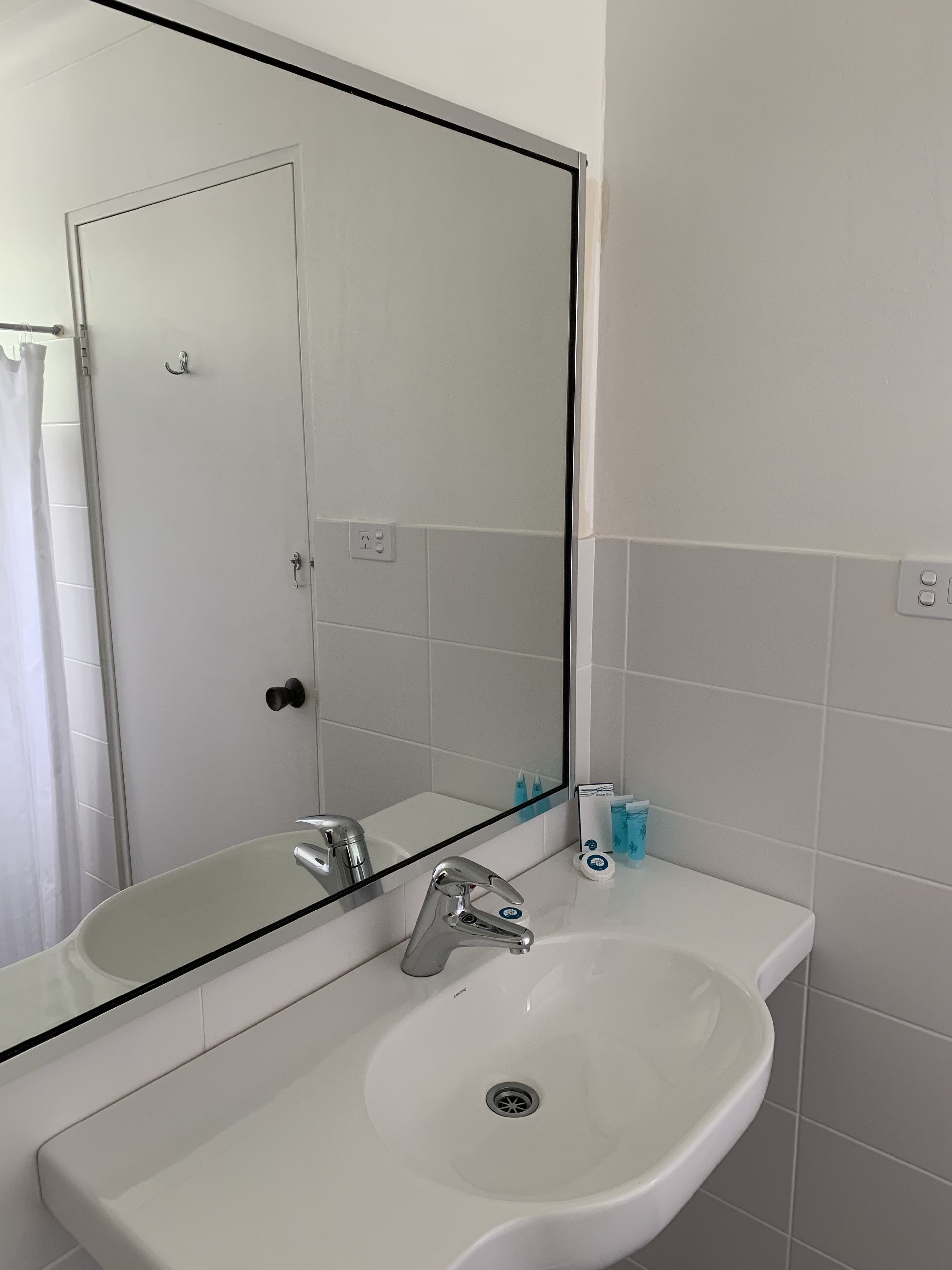 A bathroom with a white sink, a mirror, and a shower curtain.