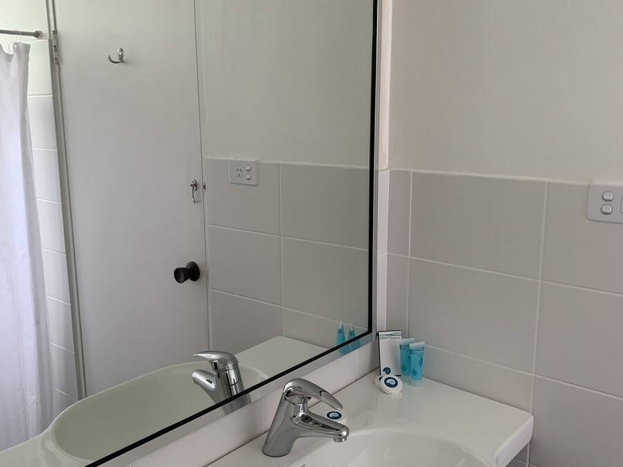 A bathroom with a white sink, a mirror, and a shower curtain.