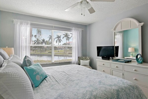 Un dormitorio con cama, televisor, cómoda y ventana con cortinas.