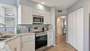 A modern kitchen with white cabinets, stainless steel appliances, and a granite countertop.
