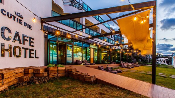 Um hotel moderno com café, área externa e um pátio coberto.