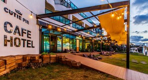A modern cafe hotel with outdoor seating and a covered patio area. - Cutie Pie Hotel (Jeju City)