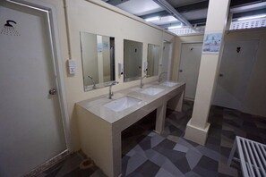 Des toilettes publiques équipées de trois lavabos, de miroirs et d’une douche.