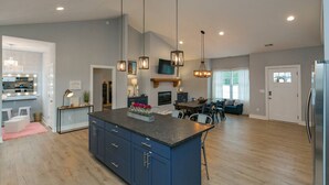 A spacious kitchen with a central island, pendant lighting, and a dining area with a sofa and chairs. - BNA Blue Retreat, Game Room, Hot Tub (Nashville)