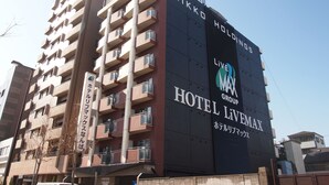A multi-story hotel building with balconies, a prominent sign for Hotel Livemax, and a logo for the LiveMAX Group. - Hotel Livemax BUDGET Namba (Osaka)