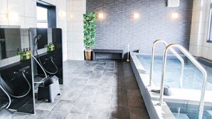 A modern bathroom with a glass-enclosed shower, a black sink, and a large mirror.