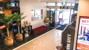 A hotel lobby with a reception desk, a red sofa, and a 'LIVE MAX' sign.