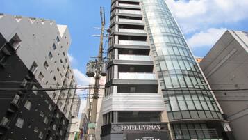 Un edificio moderno con fachada de vidrio curva y un letrero que indica Hotel Livemax y Max Cafe.