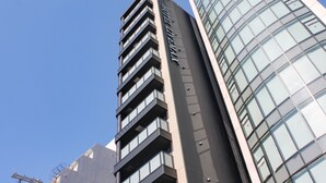 Un edificio alto con varios pisos, ventanas grandes y fachada de vidrio curva.