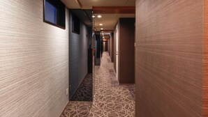 Un pasillo de hotel con alfombra estampada, paredes de madera y puertas que dan a las habitaciones.