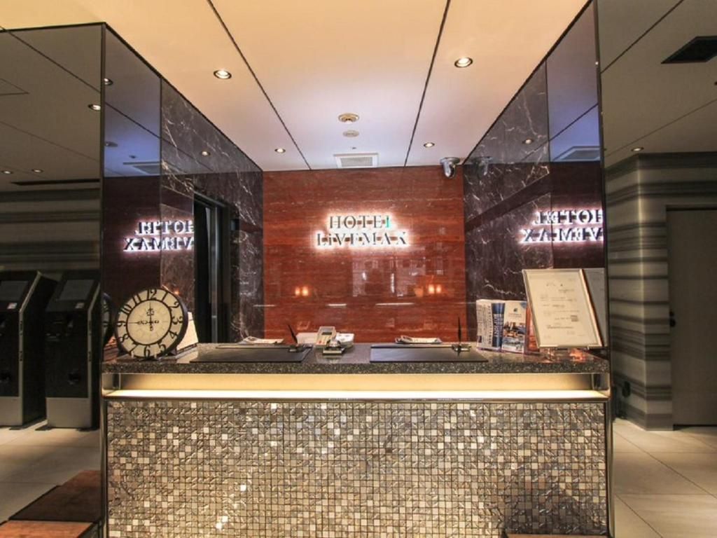 A hotel reception area with a modern design, featuring a reception desk, a clock, and a sign with the hotel's name.