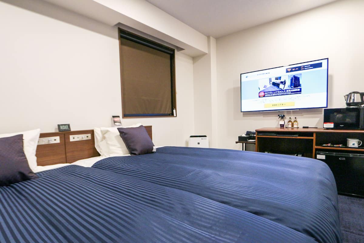 Ein Hotelzimmer mit einem großen Bett, einem an der Wand befestigten Fernseher, einer Kaffeemaschine und einem kleinen Kühlschrank.