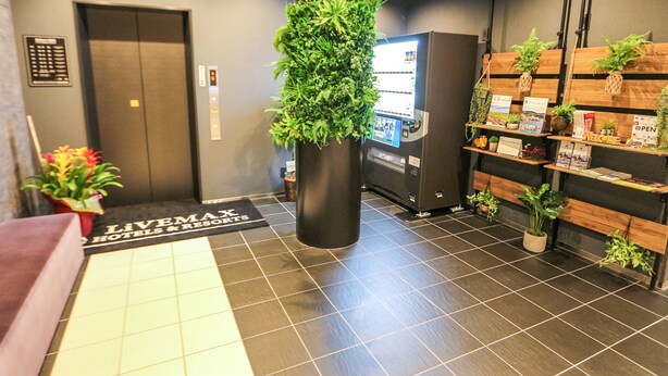Ein Empfangsbereich mit einer digitalen Kiosk, einem Verkaufsautomaten, einem Empfschalter und einem Schild für LiveMax Hotels & Resorts.