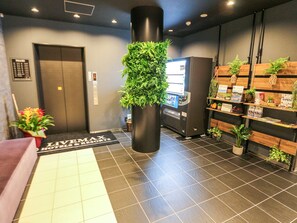 Un área de recepción con un quiosco digital, una máquina expendedora, un mostrador de recepción y un letrero para LiveMax Hotels & Resorts.