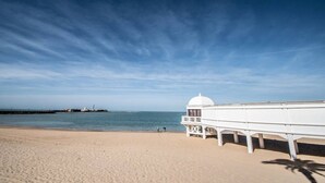 A beach with a white structure, likely a lifeguard tower, and a clear sky. - Apartamento Musa Catalina (Cádiz)