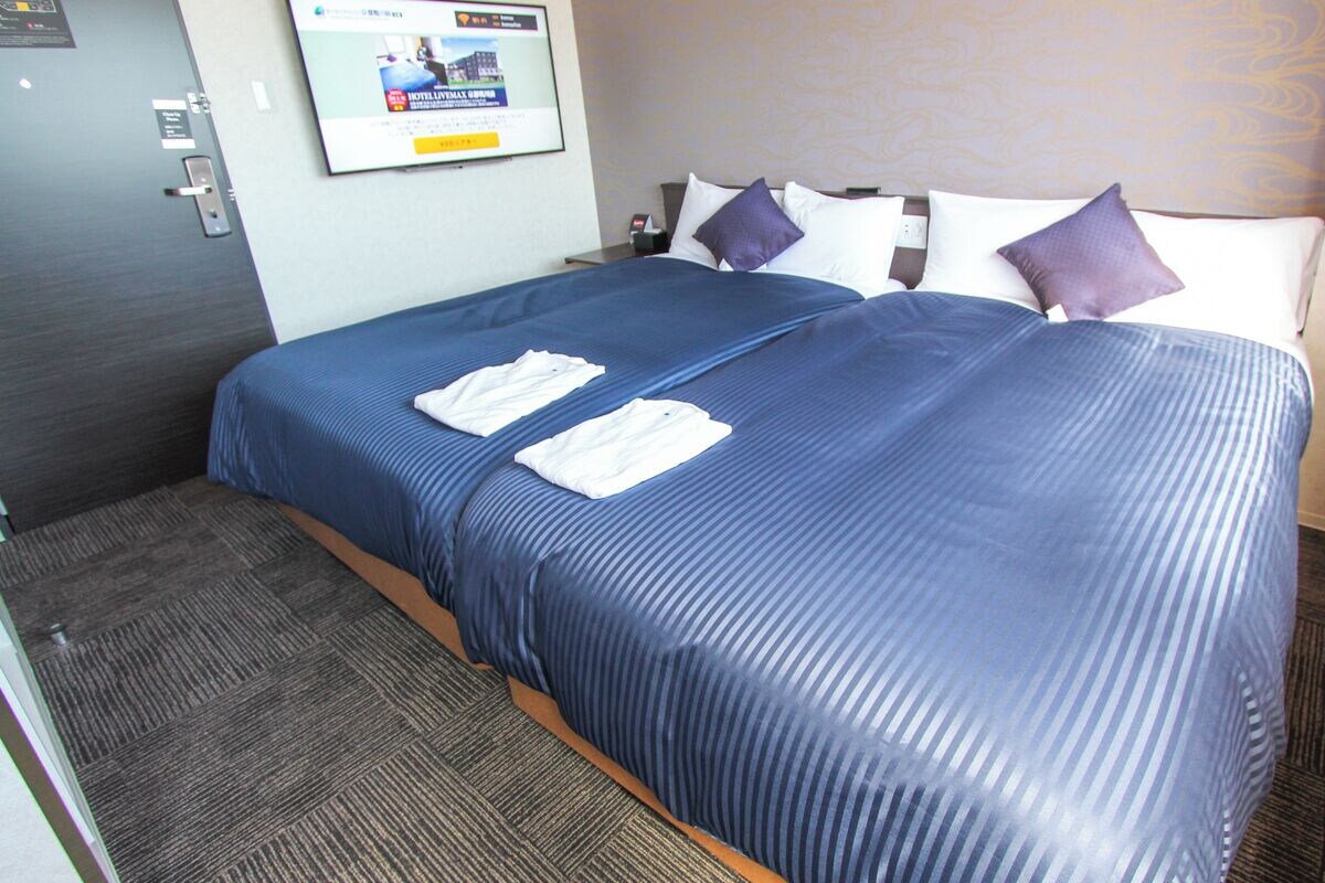 Habitación de hotel con cama, televisor de pared y puerta con cerradura.