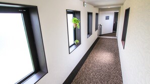 A hallway with large windows, a patterned carpet, and a plant in one of the windows. - HOTEL LiVEMAX Kyoto Kamogawamae (Kyoto)
