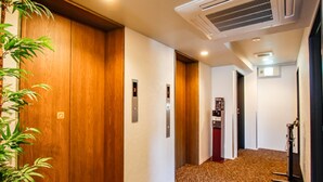 A hallway with wooden doors, an elevator, and a vending machine. - HOTEL LiVEMAX Kyoto Kamogawamae (Kyoto)