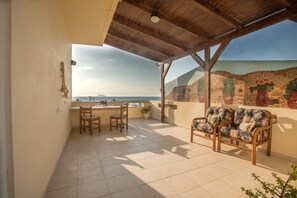 A covered patio with a view of the sea, a dining table with chairs, and a seating area with a sofa. - Kalamaki Sight (Faistos)