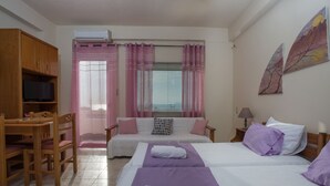 A bedroom with two beds, a TV, a desk, and a window with curtains. - Kalamaki Sight (Faistos)