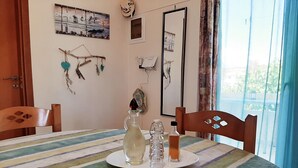 A dining table with a striped tablecloth, a plate of bread rolls, a pitcher, and salt and pepper shakers. - Kalamaki Sight (Faistos)