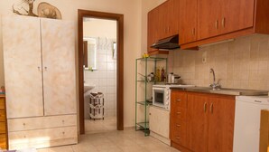 A compact kitchen with wooden cabinets, a microwave, and a sink. - Kalamaki Sight (Faistos)