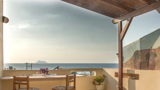 A balcony with a table and chairs, a potted plant, and a view of the sea. - Kalamaki Sight (Faistos)