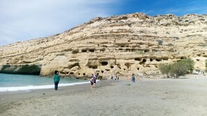 A beach with a rocky cliff in the background. - Kalamaki Sight (Faistos)