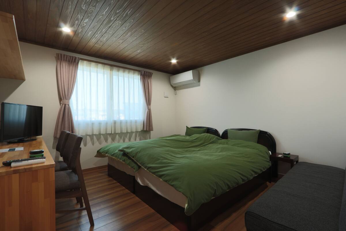 A bedroom with a bed, a desk with a television, and a chair.