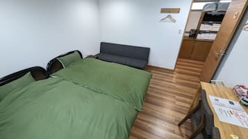 A small, neatly arranged bedroom with a bed, a desk, and a wardrobe.