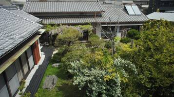 Una casa tradicional japonesa con tejado de cerámica, rodeada de abundante vegetación y un pequeño jardín.
