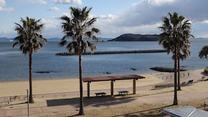 Una playa con palmeras, un muelle de madera y un área de descanso cubierta.