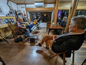 A group of people sitting and playing guitars in a room with wooden floors and tables. - guesthouse KEY's (Nishio)