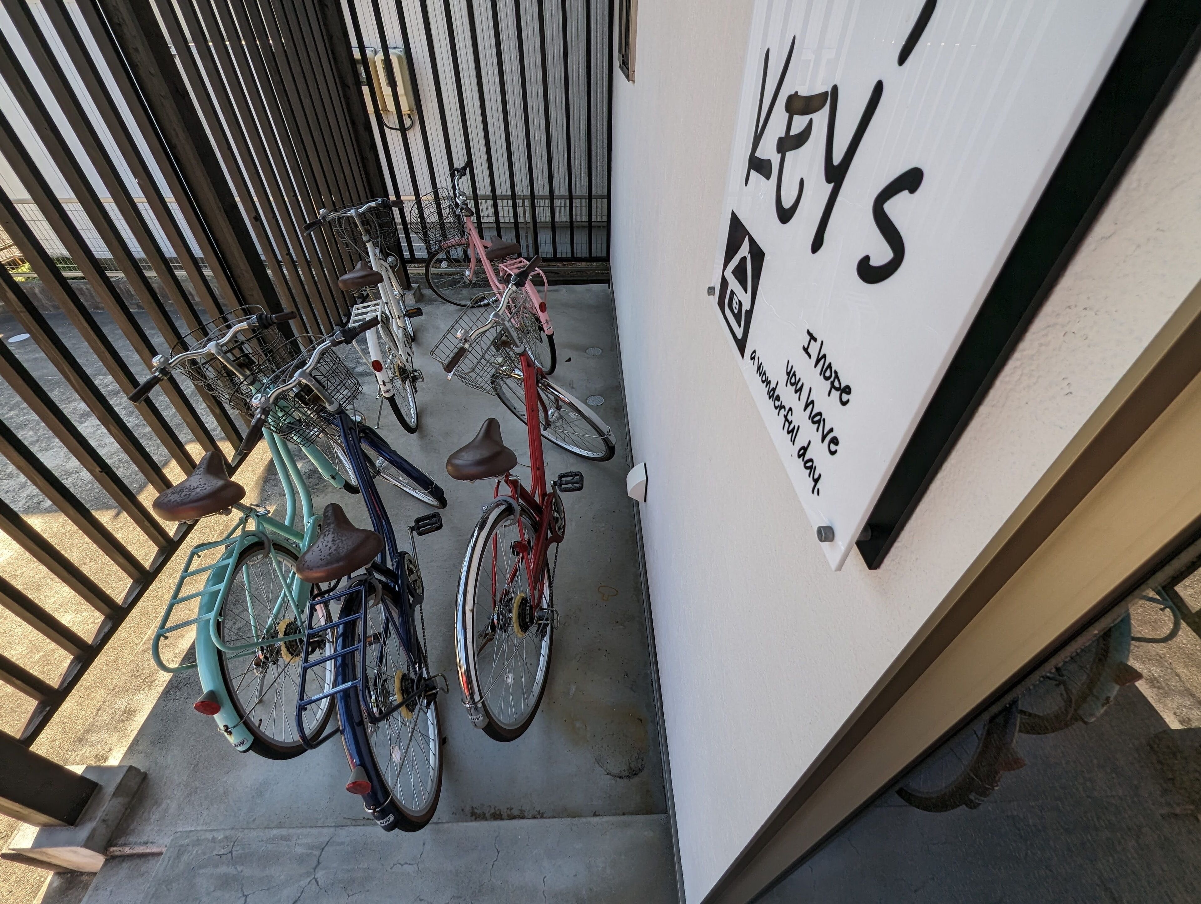 Bicicletas estacionadas frente a un edificio con un letrero que dice 'KEYS I hope you have a wonderful day'.