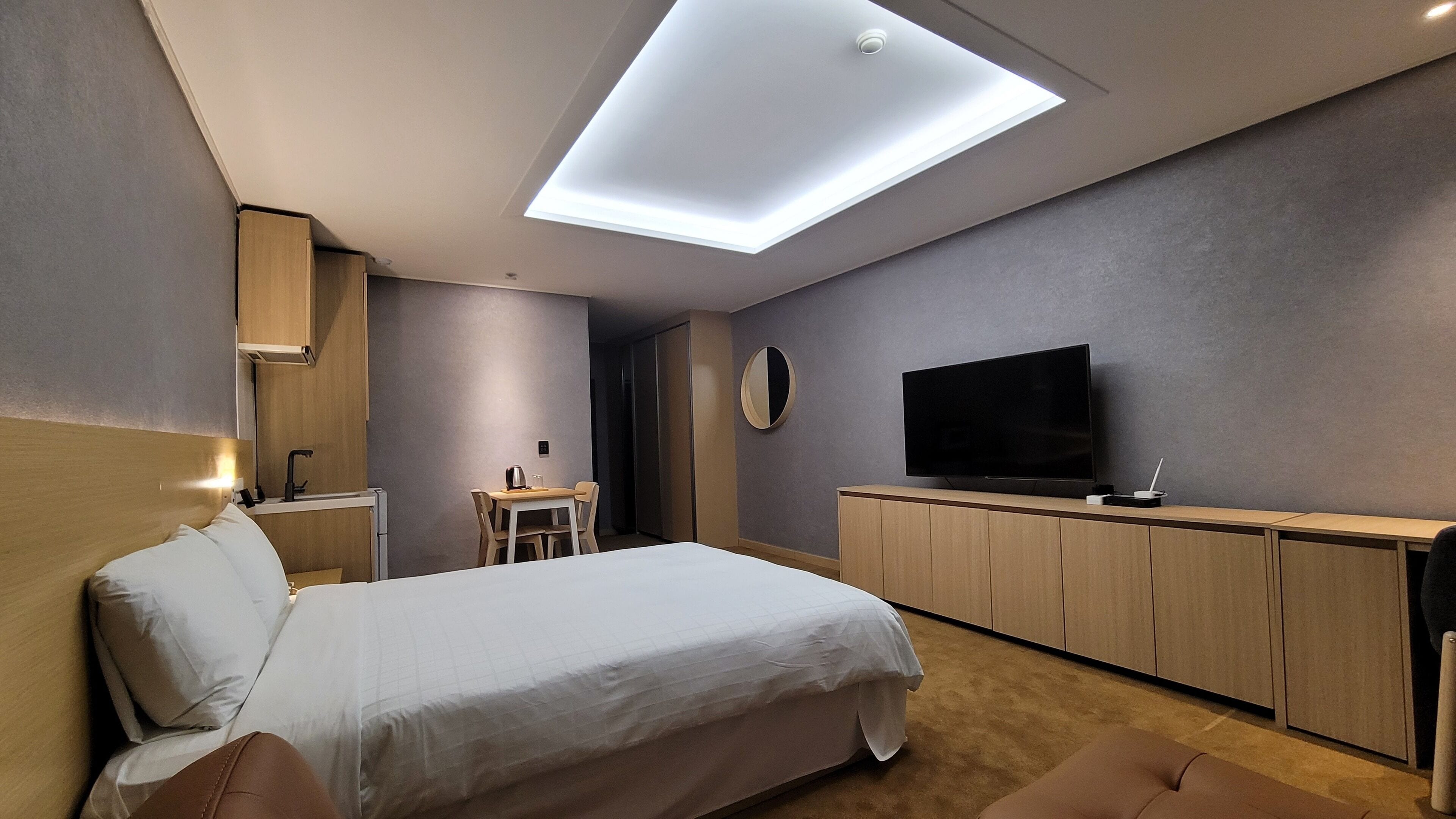 Una habitación de hotel moderna con una cama, un escritorio, un televisor y un tragaluz.