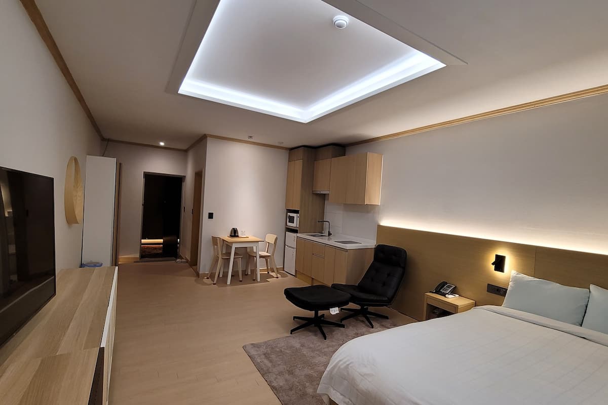 Een moderne hotelkamer met een groot bed, een bureau met stoel, een kitchenette en een televisie.