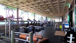 Une salle de sport équipée de tapis de course, d’appareils de musculation et de poids libres.