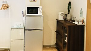 Une cuisine compacte équipée d’un réfrigérateur, d’un four à micro-ondes et d’un petit plan de travail agrémenté d’une plante et de quelques bocaux.