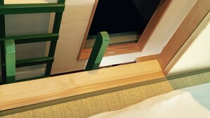 Un lit superposé avec une échelle, une petite fenêtre et un cadre de porte en bois.