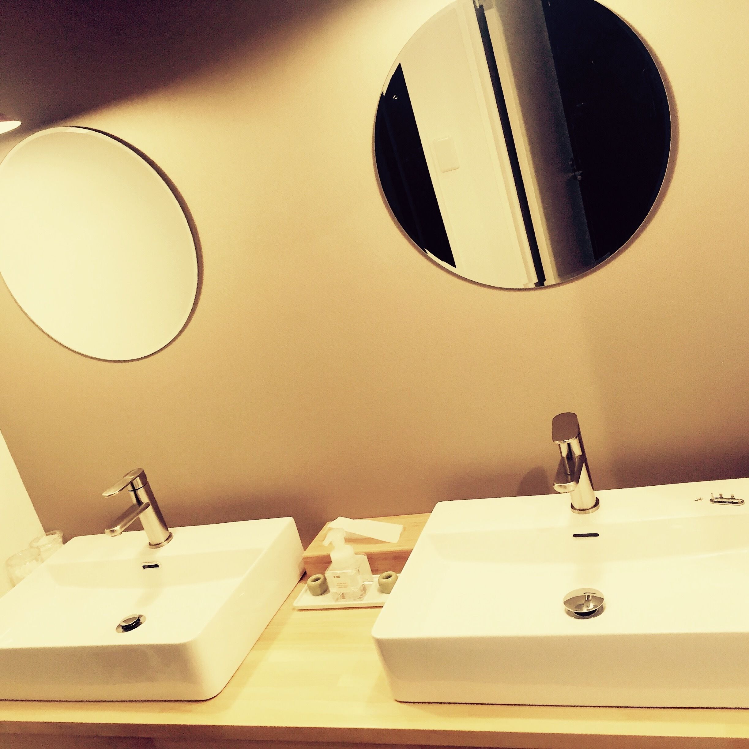A bathroom with two sinks and two round mirrors.