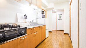 A modern kitchen with wooden cabinets, a gas stove, a microwave, and a sink. - Yanbaru Forest Hills (Motobu)