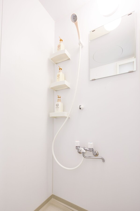 A bathroom with a shower, a toilet, and a mirror. - Yanbaru Forest Hills (Motobu)