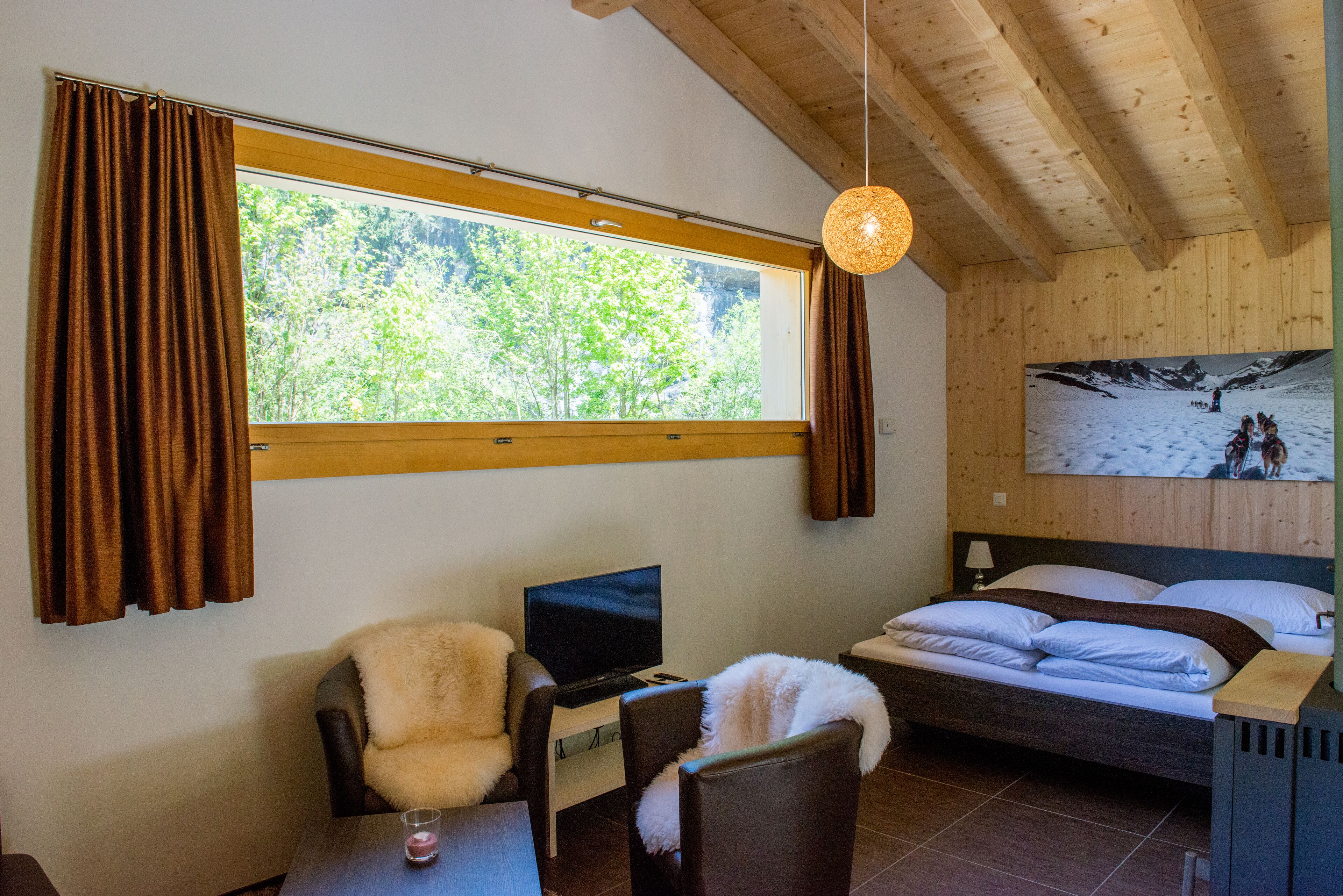Une chambre à coucher avec un lit, une chaise, un bureau avec un ordinateur, une fenêtre avec des rideaux et un tableau accroché au mur.