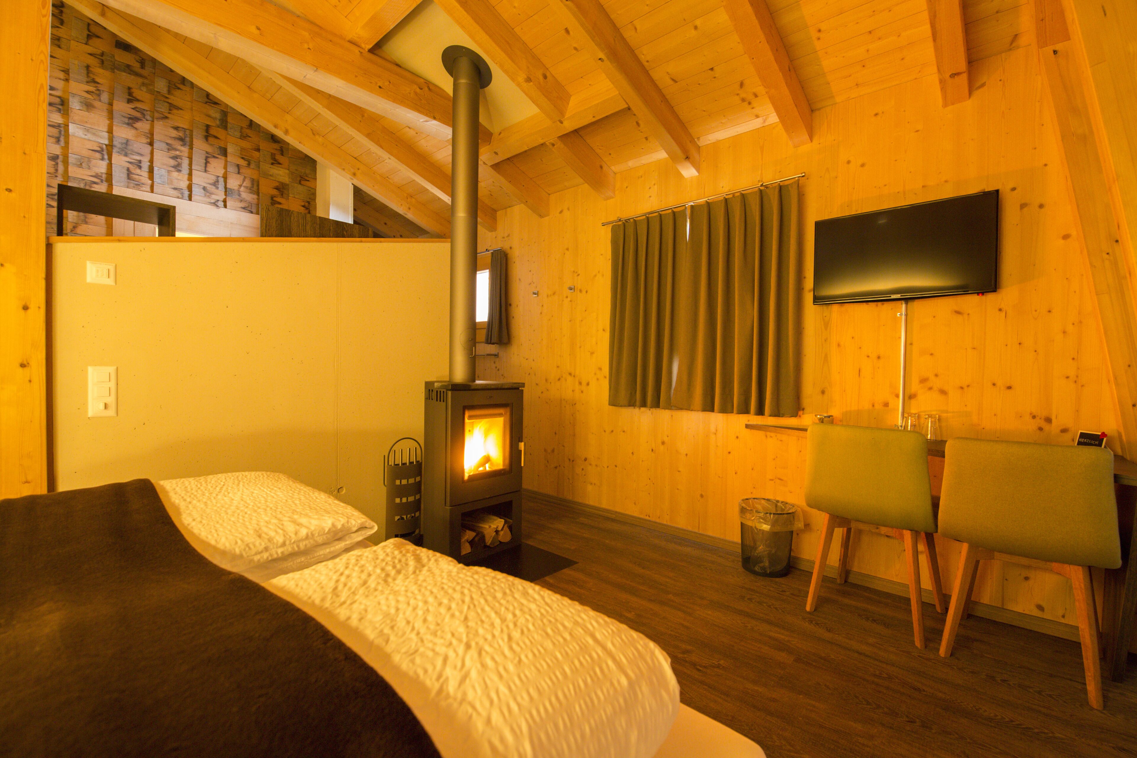 Una habitación acogedora con cama, chimenea, televisión y ventana con cortinas.