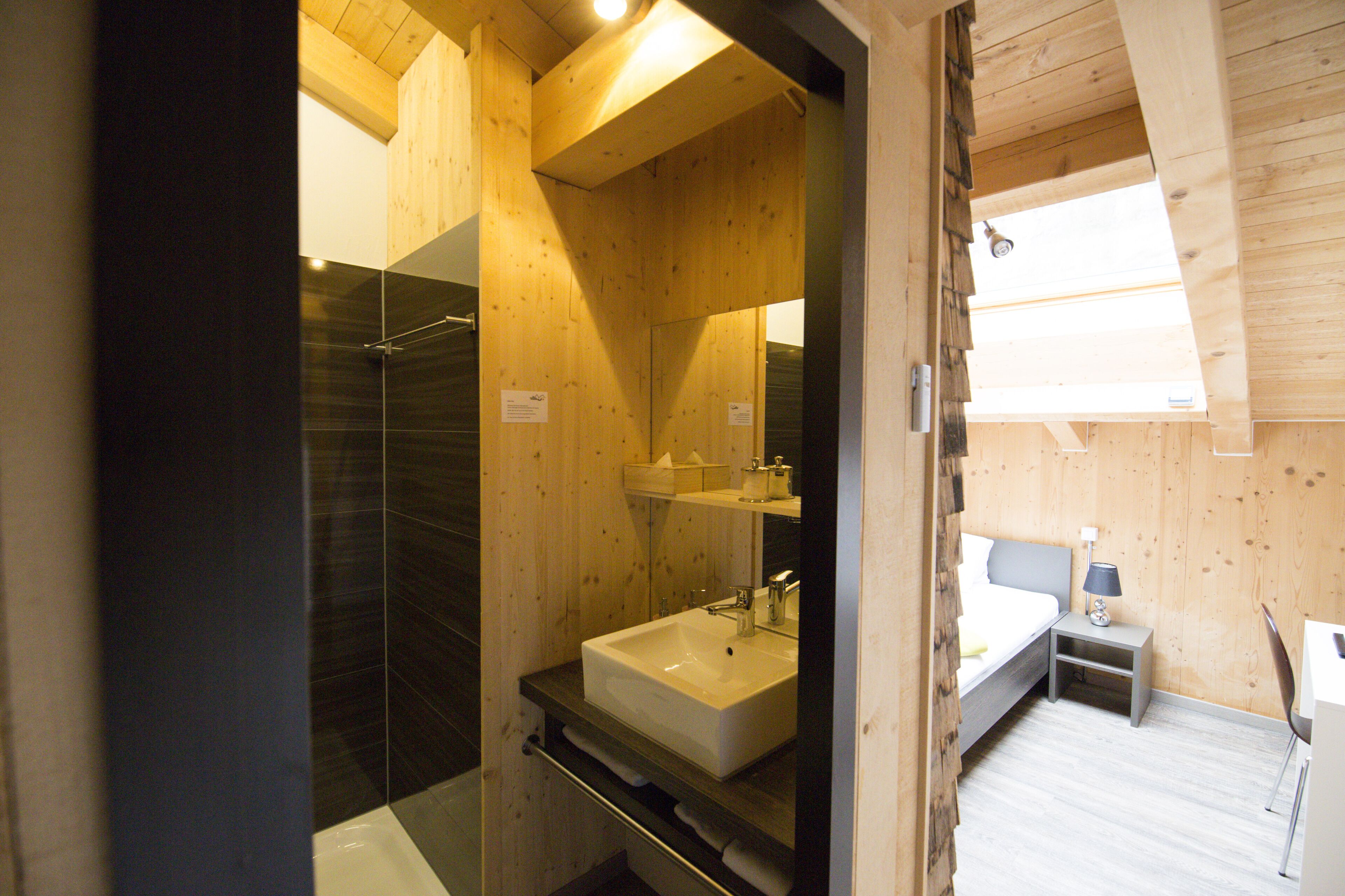 Un baño moderno con un lavabo grande, espejo y ducha.