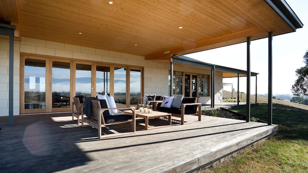 Un espacio de estar al aire libre cubierto, con mobiliario de madera y vistas al paisaje.