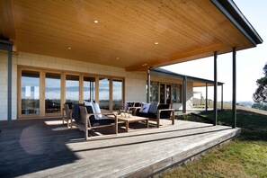 A covered outdoor seating area with wooden furniture and a view of the landscape. - Drom Aluinn B & B (Acheron)