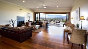 Un salón amplio con un sofá grande, una televisión y vistas al exterior.